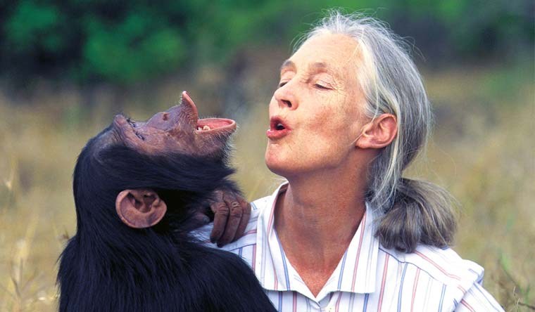 Jane Goodall loking happy and posing with a monkey